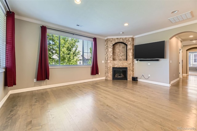 10127 Bluffmont Ln, Lone Tree, CO 80124 - unfurnished living room featuring arched walkways, crown molding, wood finished floors, a tile fireplace, and recessed lighting