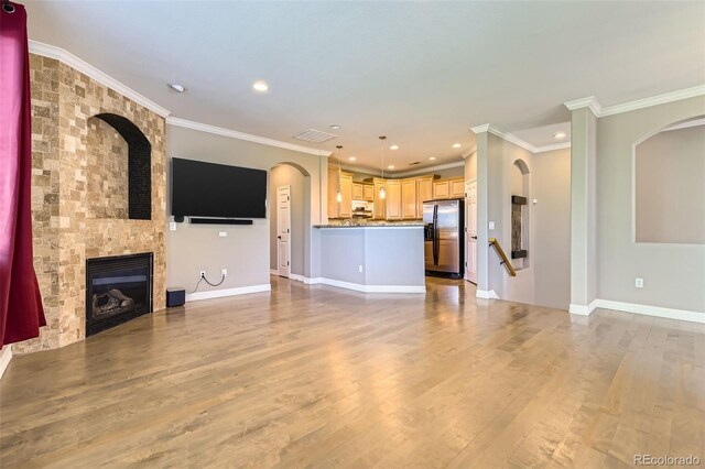10127 Bluffmont Ln, Lone Tree, CO 80124 - unfurnished living room with wood finished floors, ornamental molding, a large fireplace, recessed lighting, and arched walkways