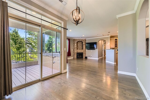 10127 Bluffmont Ln, Lone Tree, CO 80124 - unfurnished dining area with a chandelier, ornamental molding, a fireplace, dark wood finished floors, and arched walkways