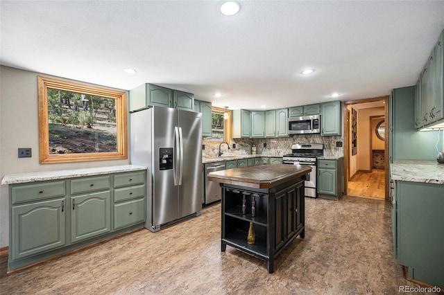 44 Conestoga Ct, Bailey, CO 80421 - kitchen featuring stainless steel appliances, green cabinetry, a sink, backsplash, and a center island