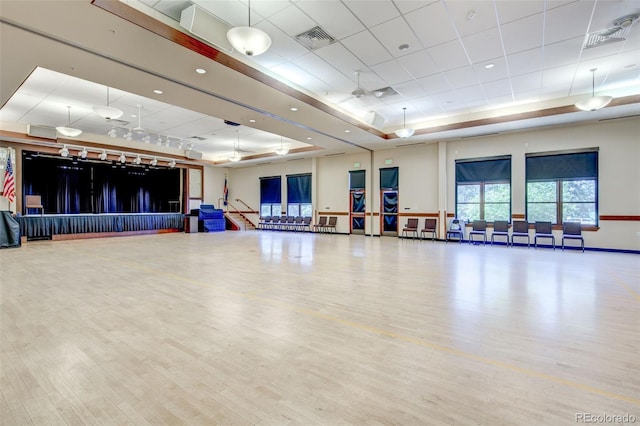 workout area featuring a raised ceiling, hardwood / wood-style floors, and ceiling fan