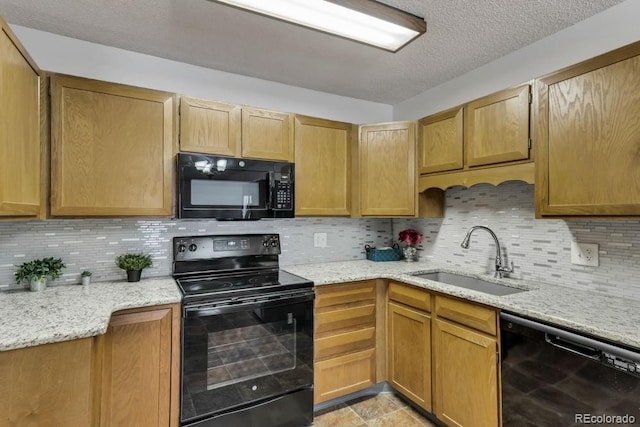 kitchen featuring sink, backsplash, light stone counters, and black appliances