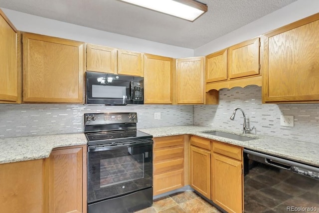 kitchen featuring tasteful backsplash, sink, light stone counters, and black appliances