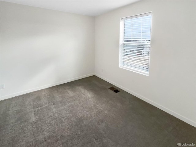 spare room featuring dark colored carpet