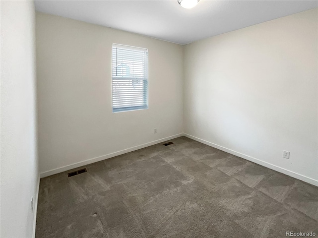 spare room featuring dark carpet