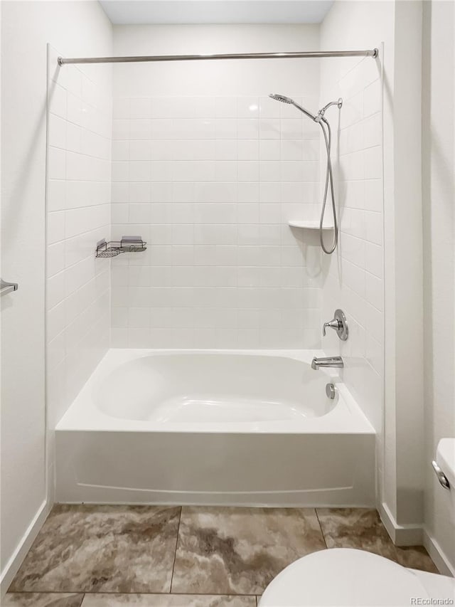 bathroom with toilet and tiled shower / bath