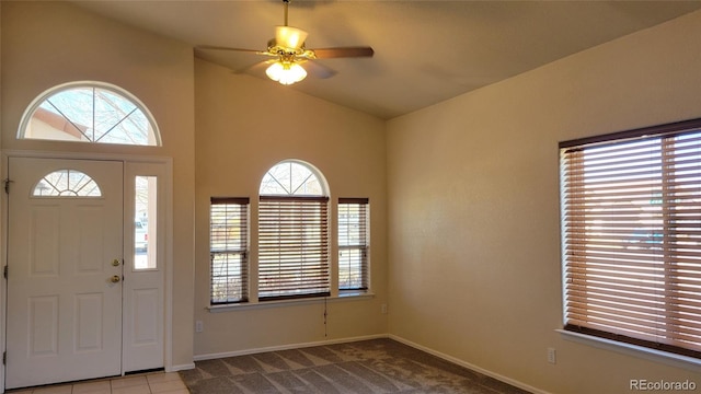 carpeted entryway with lofted ceiling, baseboards, and ceiling fan
