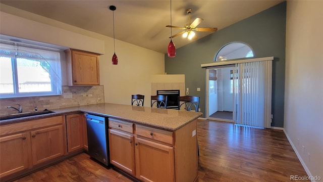 kitchen with dishwasher, a sink, a tiled fireplace, ceiling fan, and a peninsula