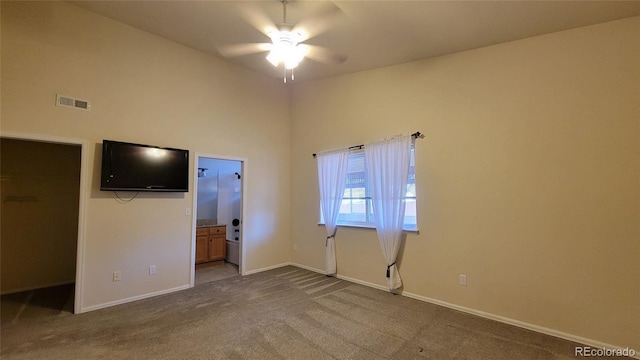 interior space with visible vents, baseboards, carpet floors, connected bathroom, and high vaulted ceiling