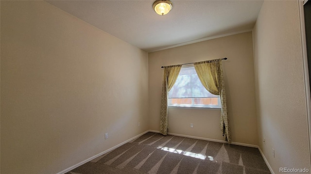 carpeted spare room featuring baseboards