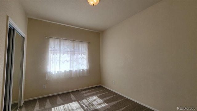 unfurnished room featuring carpet and baseboards