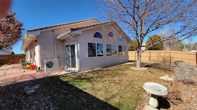 back of property with ac unit, a tiled roof, a fenced backyard, stucco siding, and a patio