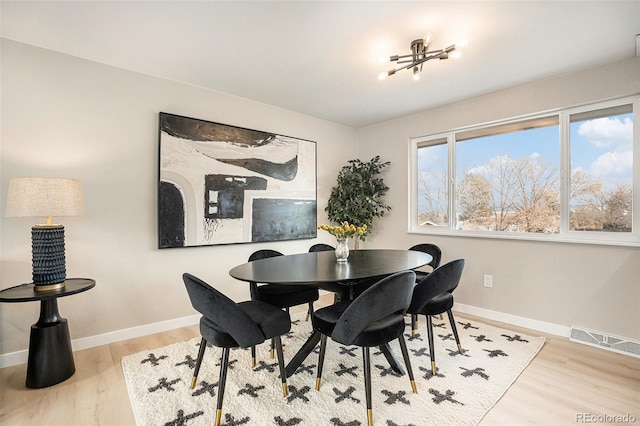 dining space with light hardwood / wood-style flooring and a notable chandelier