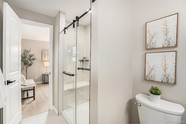 bathroom featuring a shower with door and toilet