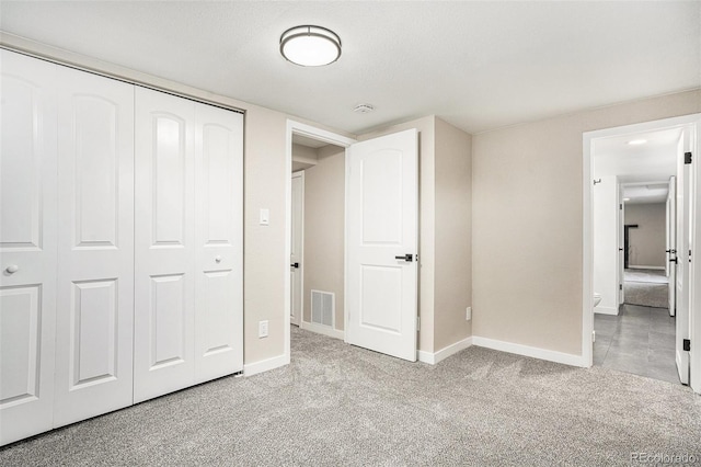 unfurnished bedroom with light carpet and a closet