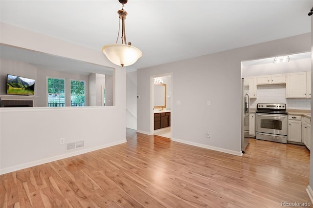 interior space with light wood-style floors, visible vents, and baseboards