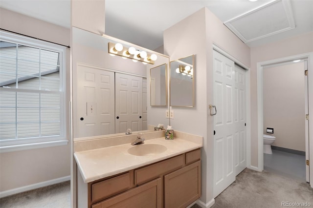 bathroom featuring a closet, vanity, toilet, and a healthy amount of sunlight