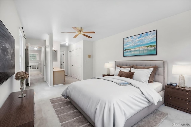 bedroom with a closet, light carpet, ceiling fan, and ensuite bathroom