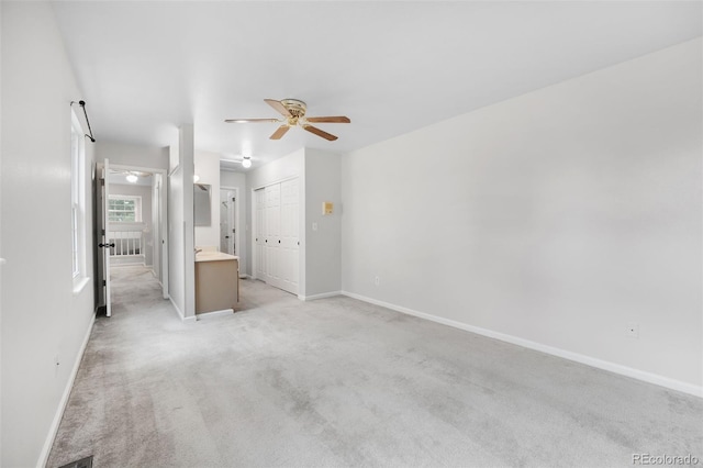 interior space with ceiling fan, baseboards, and light colored carpet