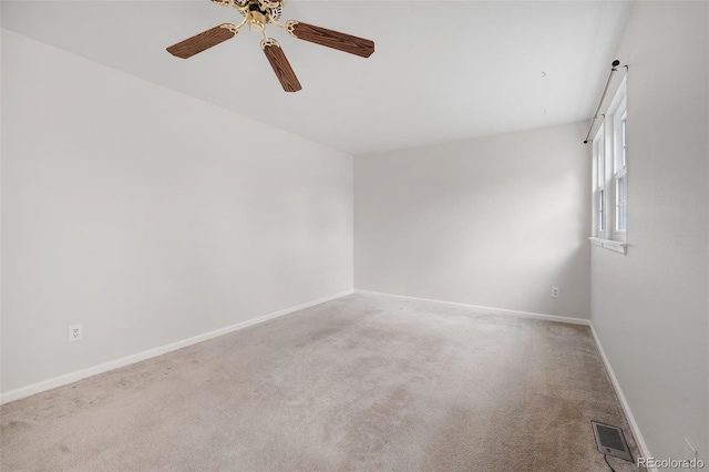 carpeted spare room with baseboards, visible vents, and ceiling fan