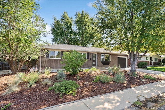 ranch-style house featuring concrete driveway, brick siding, and an attached garage