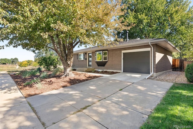 ranch-style home featuring a garage, brick siding, driveway, and fence