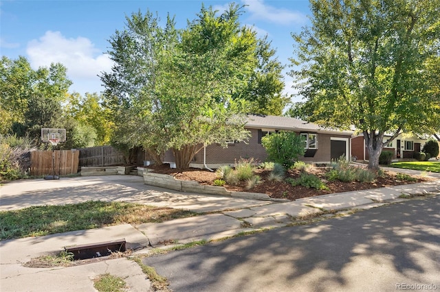 view of front facade with an attached garage, fence, concrete driveway, and brick siding