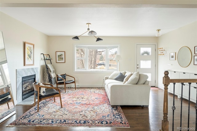 living area with a fireplace, baseboards, and dark wood finished floors