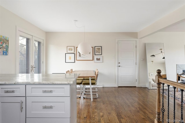 kitchen featuring dark wood-style floors, pendant lighting, baseboards, and light stone countertops