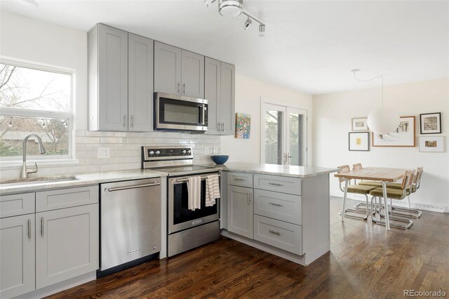 kitchen featuring stainless steel appliances, plenty of natural light, a sink, and a peninsula