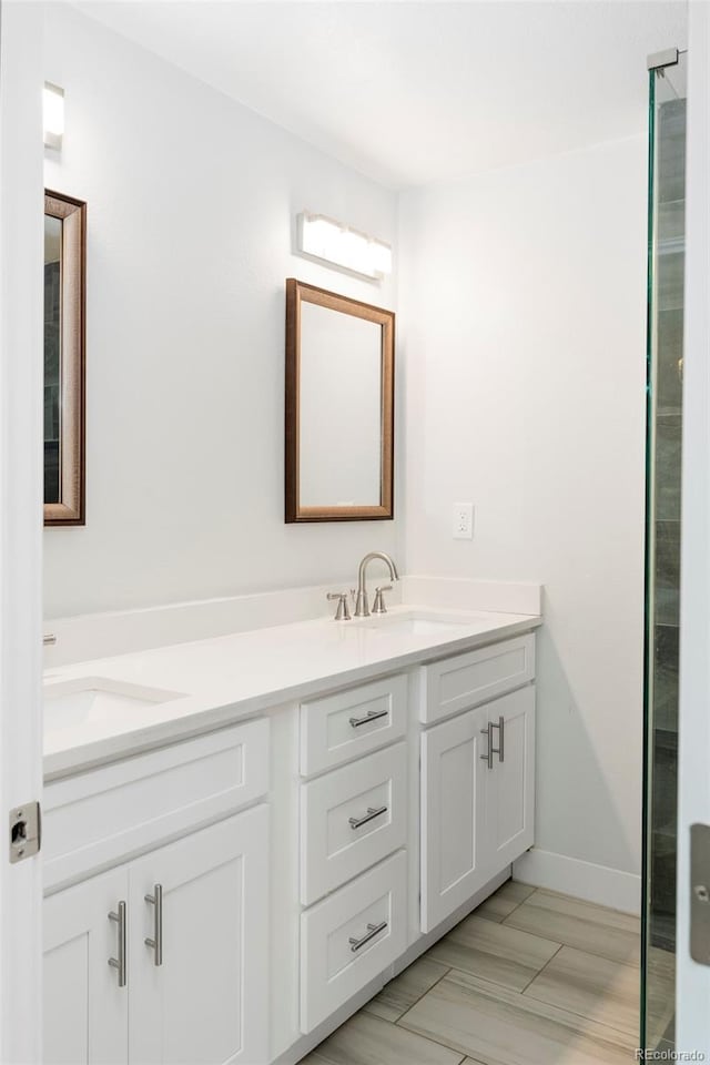 bathroom with double vanity, baseboards, and a sink