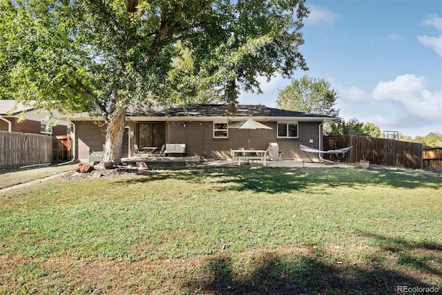 back of property featuring a yard, a fenced backyard, a patio, and brick siding