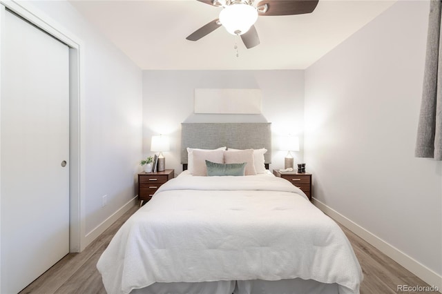 bedroom with a closet, baseboards, light wood-style floors, and a ceiling fan