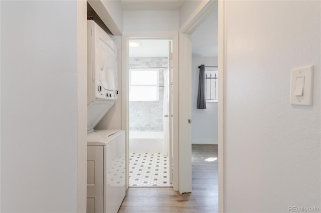 laundry area featuring stacked washer / dryer, laundry area, and wood finished floors