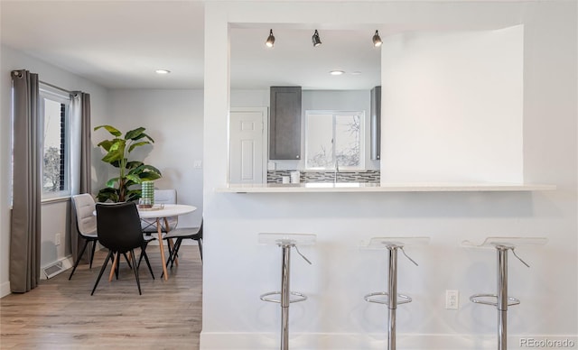 kitchen featuring light wood-type flooring, light countertops, visible vents, and a breakfast bar area