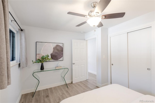 bedroom with baseboards, a ceiling fan, wood finished floors, and a closet