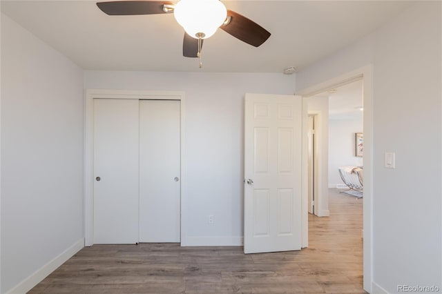 unfurnished bedroom featuring wood finished floors, a closet, a ceiling fan, and baseboards