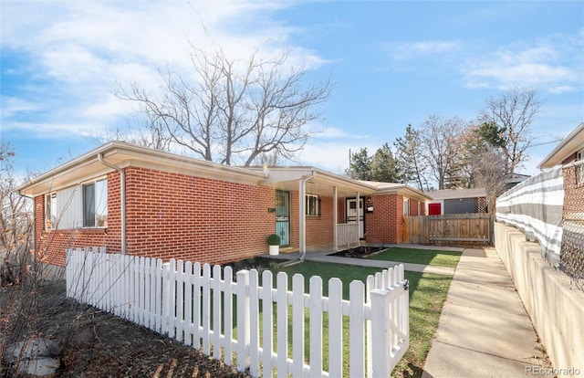 view of front of home with a front lawn, brick siding, a porch, and a fenced front yard