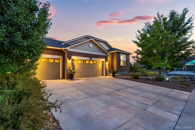 view of front of house with an attached garage, concrete driveway, and brick siding