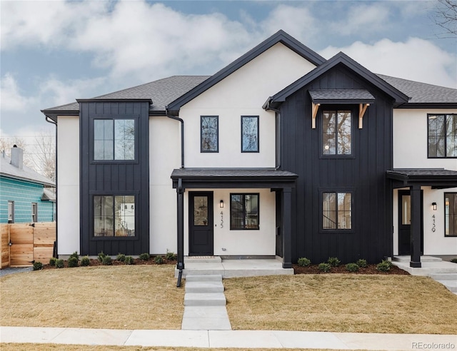 modern farmhouse style home with stucco siding, board and batten siding, a front lawn, and fence