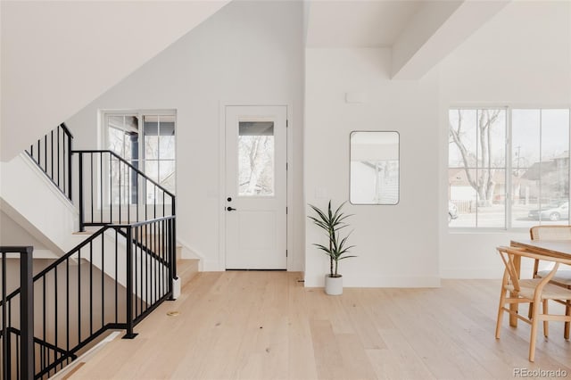 foyer entrance featuring vaulted ceiling, stairway, wood finished floors, and baseboards