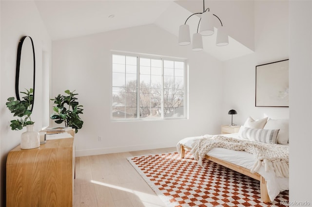 bedroom featuring baseboards, lofted ceiling, and wood finished floors