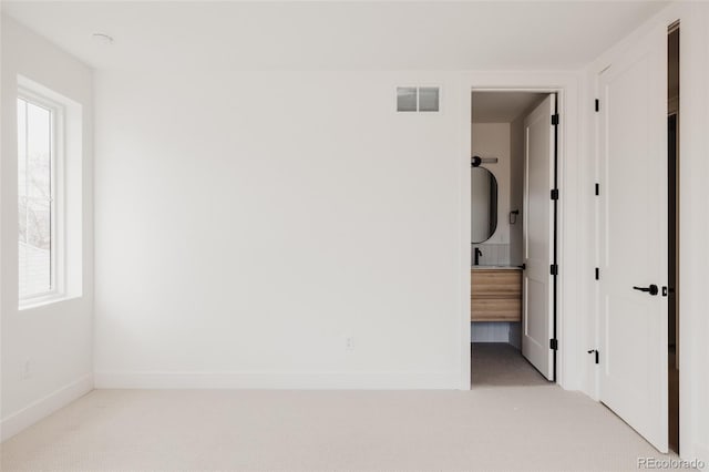 spare room featuring visible vents, light colored carpet, and baseboards