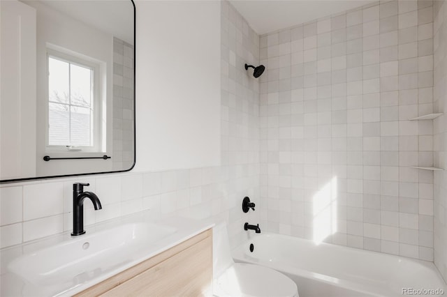 bathroom featuring tile walls, toilet, vanity, and washtub / shower combination