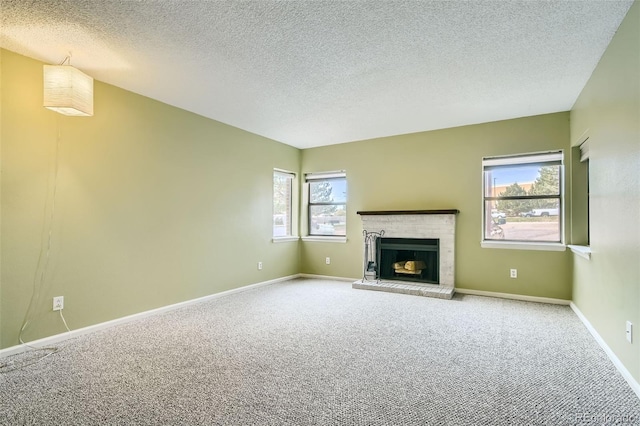 unfurnished living room with carpet, a healthy amount of sunlight, a textured ceiling, and a fireplace