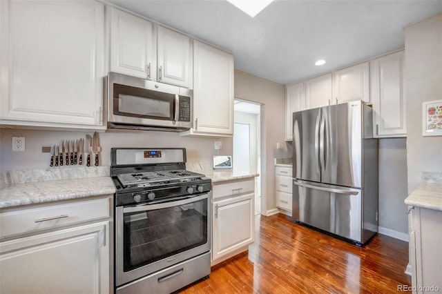 kitchen with white cabinets, light wood-style floors, baseboards, and stainless steel appliances