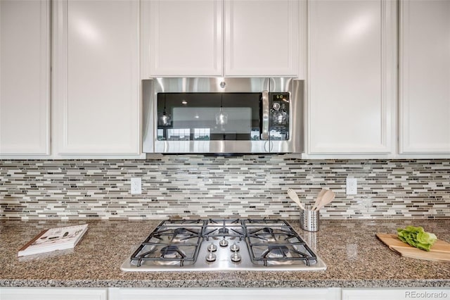 10387 Harrisburg St, Parker, CO 80134 - kitchen featuring appliances with stainless steel finishes, white cabinetry, tasteful backsplash, and dark stone countertops