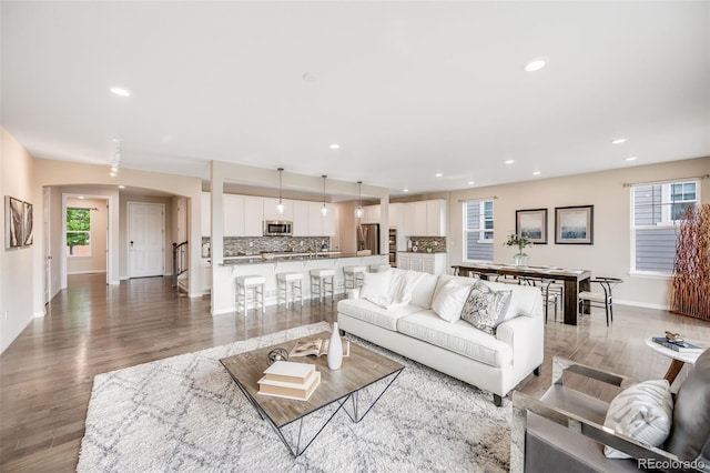10387 Harrisburg St, Parker, CO 80134 - living room featuring recessed lighting, arched walkways, plenty of natural light, and wood finished floors