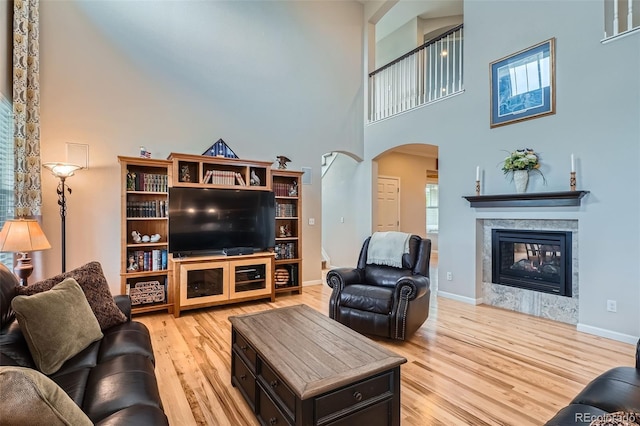 23503 E Minnow Dr, Aurora, CO 80016 - living area with arched walkways, a towering ceiling, wood finished floors, and a multi sided fireplace