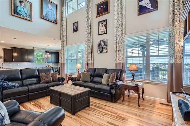 23503 E Minnow Dr, Aurora, CO 80016 - living room with light wood finished floors, a towering ceiling, and a chandelier